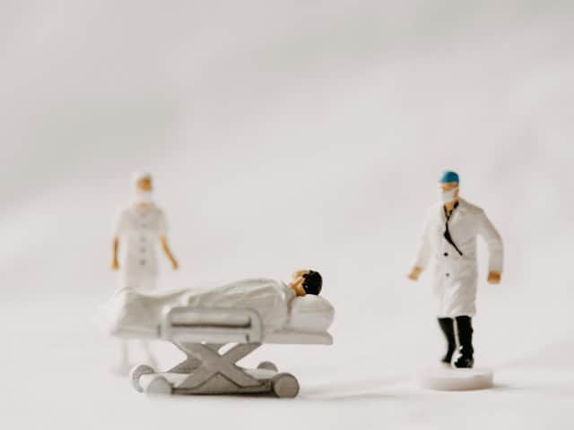 doctor and nurse figurines in front of another on a hospital bed