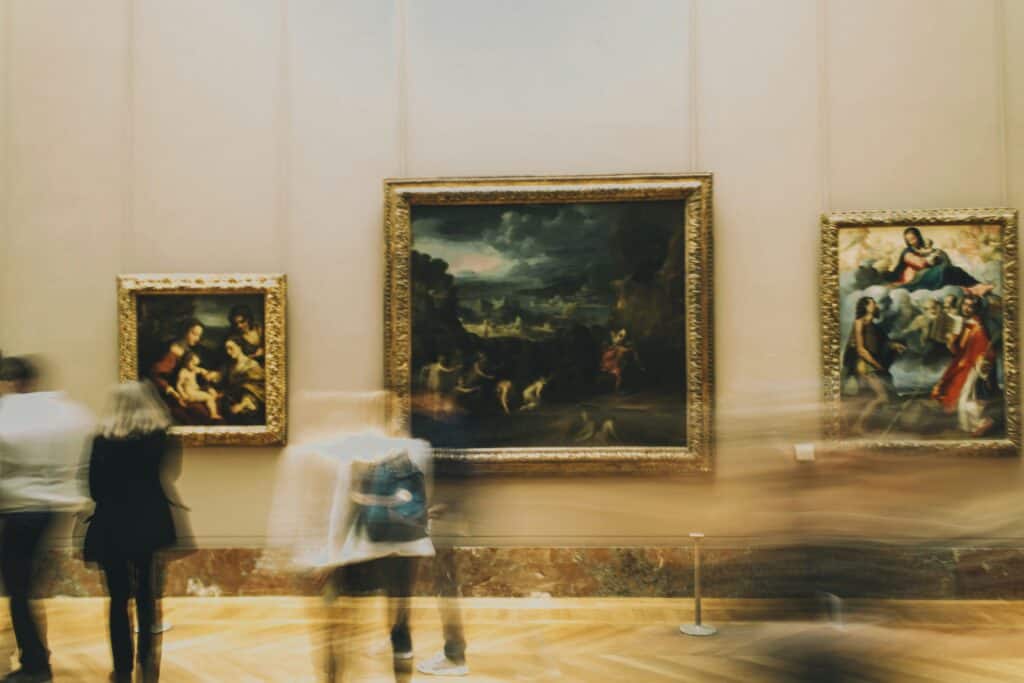 people walking past paintings in the Louvre, Paris